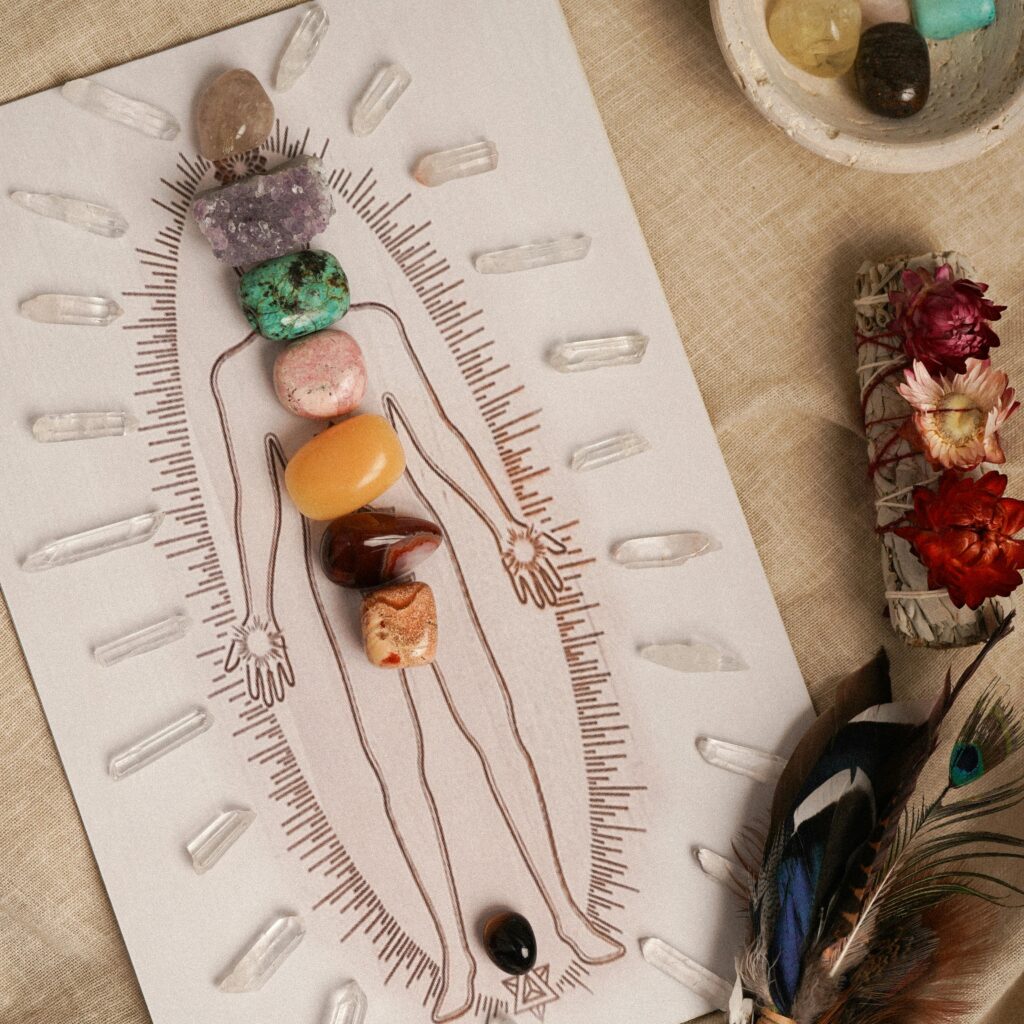 Illustration d'une silhouette humaine présentant des pierres colorées disposées sur les points des chakras, entourée de petits cristaux de quartz.